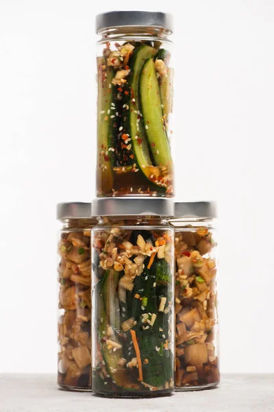Savoureux daikon radis et concombre kimchi dans des bocaux en verre isolés sur blanc — Photo de stock