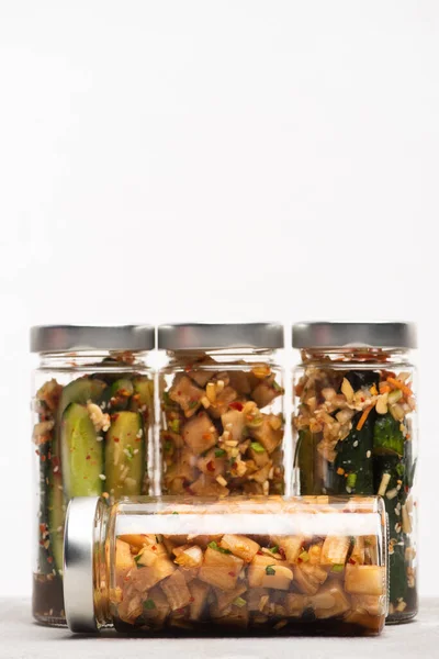 Tasty daikon radish and cucumber kimchi in jars isolated on white — Stock Photo