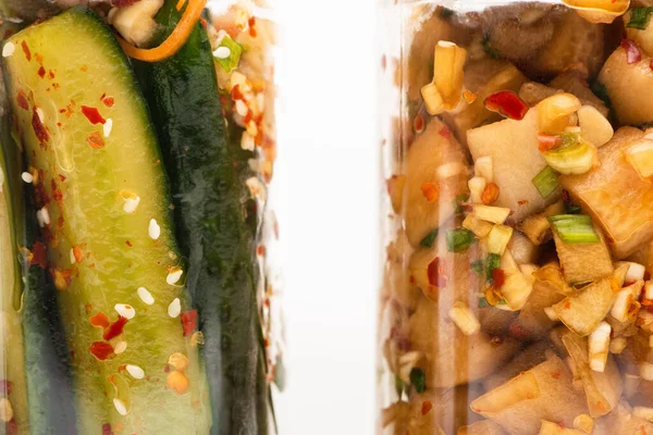 Gros plan de savoureux kimchi au concombre et radis daikon dans des bocaux en verre isolés sur du blanc — Photo de stock