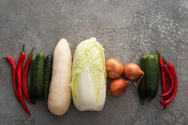 Vue de dessus des piments, concombres, radis daikon, chou chinois et oignons sur fond de béton gris — Photo de stock