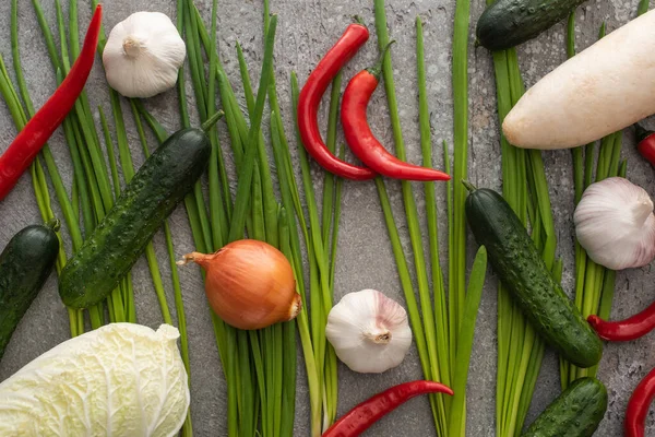 Vue de dessus des piments, oignons, concombres, ail, chou chinois et oignons verts sur fond de béton gris — Photo de stock