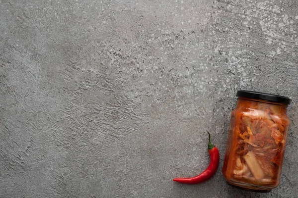 Vista superior de pimenta vermelha e jarra de kimchi no fundo de concreto cinza — Fotografia de Stock