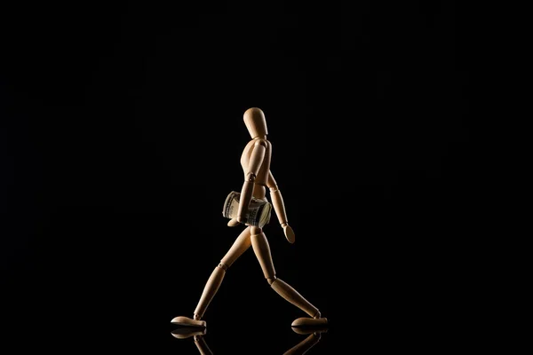 Poupée en bois imitant la marche avec de l'argent sur fond noir — Photo de stock