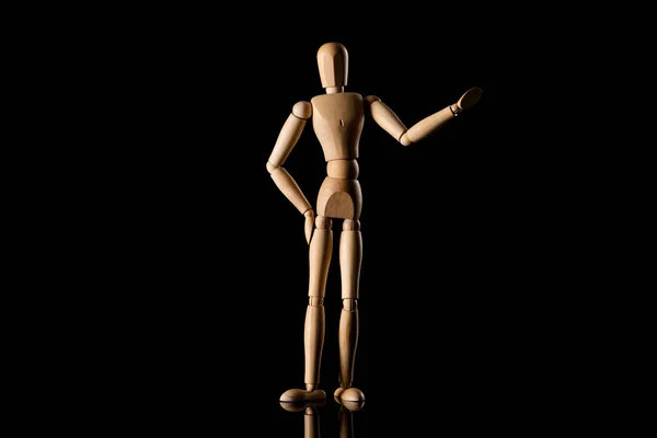 Muñeca de madera con la mano en la cadera imitando señalando con la mano sobre fondo negro - foto de stock