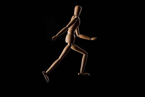 Wooden doll imitating running isolated on black — Stock Photo