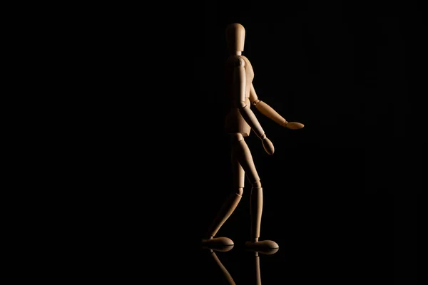 Wooden doll imitating walking on black background — Stock Photo