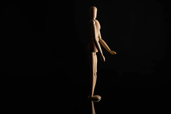 Wooden doll in standing position on black background — Stock Photo