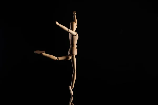 Marioneta de madera imitando el baile sobre fondo negro - foto de stock