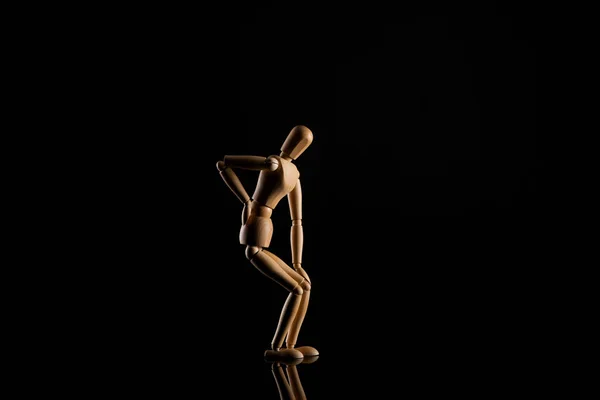 Muñeca de madera imitando el dolor de espalda sobre fondo negro - foto de stock