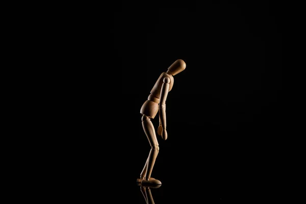 Bambola in legno in posizione appoggiata su sfondo nero — Foto stock
