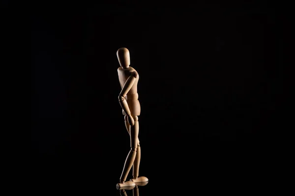 Boneca de madeira imitando inclinando-se para trás no fundo preto — Fotografia de Stock