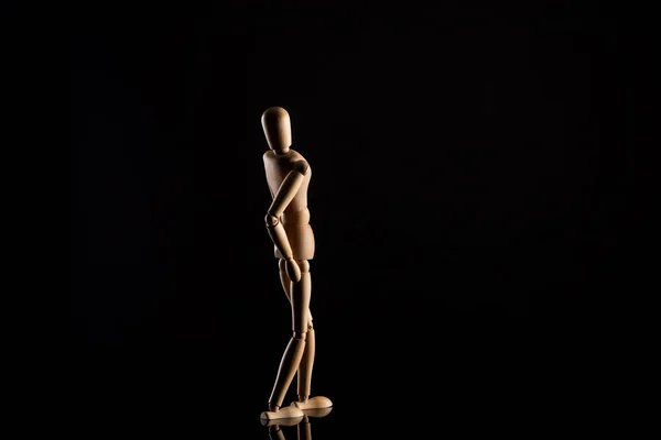 Wooden doll imitating leaning back on black background — Stock Photo