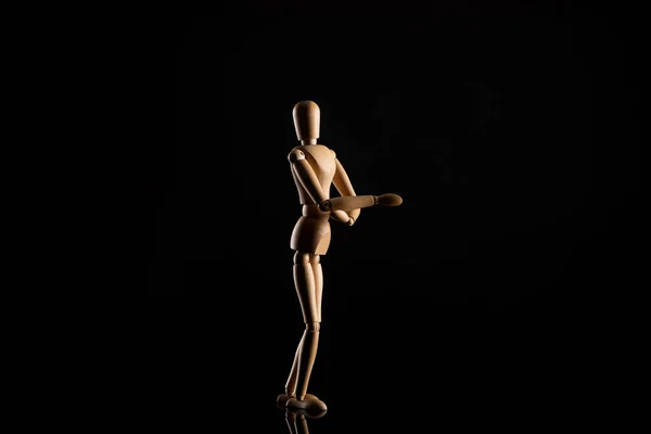 Wooden doll in standing position with outstretched hand on black background — Stock Photo