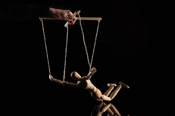 Cropped view of puppeteer holding wooden doll with ropes on black — Stock Photo