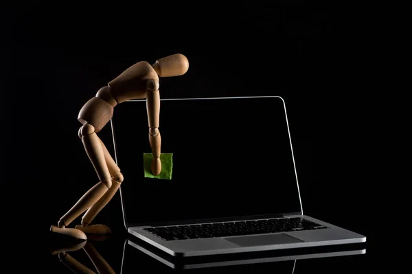 Boneca de madeira imitando pulverização laptop no fundo preto — Fotografia de Stock