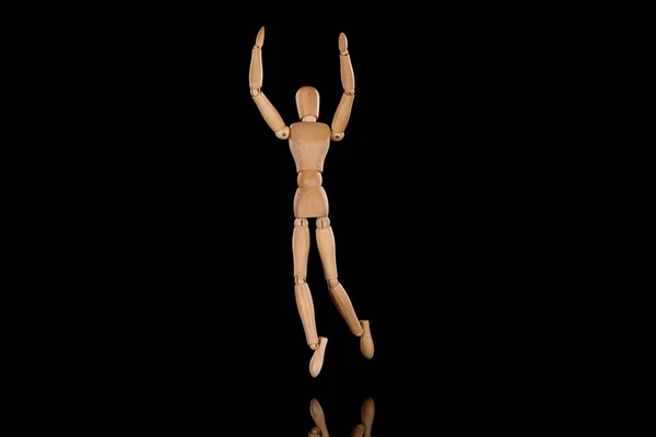 Wooden doll imitating dancing with outstretched hands on black — Stock Photo