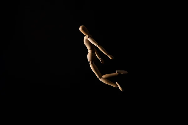 Деревянная кукла в положении падения на черном фоне — стоковое фото