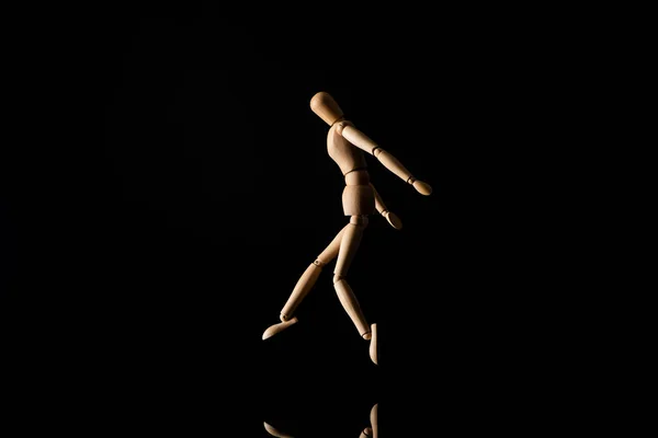 Wooden doll imitating jumping on black — Stock Photo