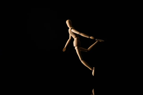 Poupée en bois en position de chute sur noir — Photo de stock