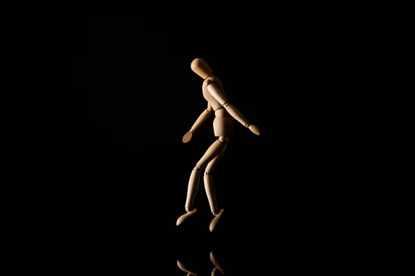 Wooden doll imitating tip toeing on black background — Stock Photo