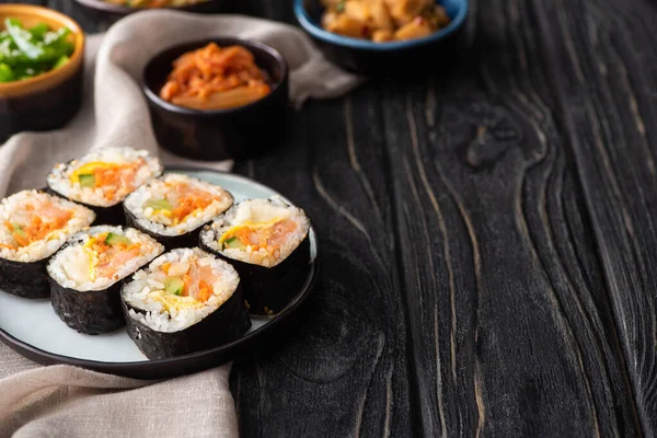 Selective focus of tasty rice rolls near korean side dishes and cotton napkin on wooden surface — Stock Photo