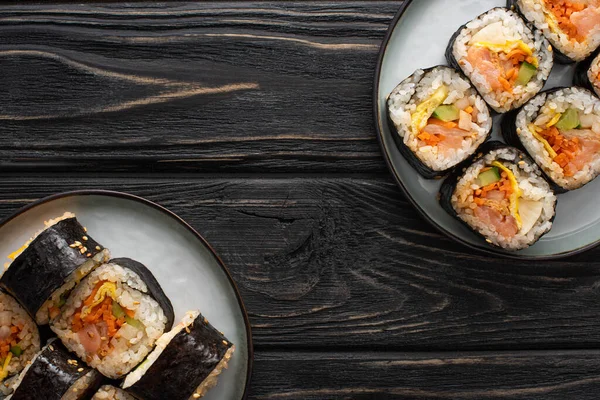 Vue de dessus des plaques avec gimbap coréen sur la surface en bois — Photo de stock