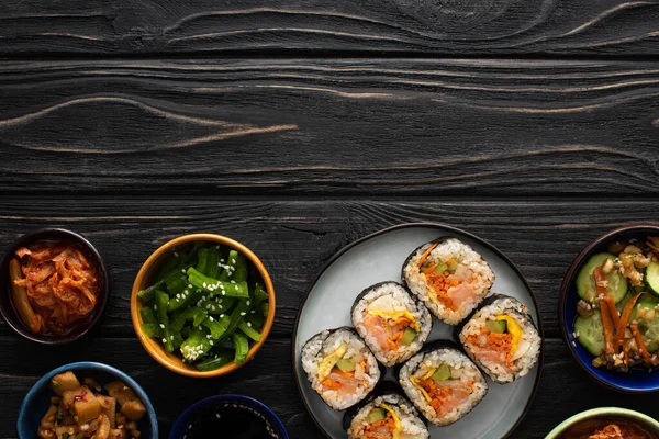 Top view of plate with korean gimbap near side dishes on wooden surface — Stock Photo