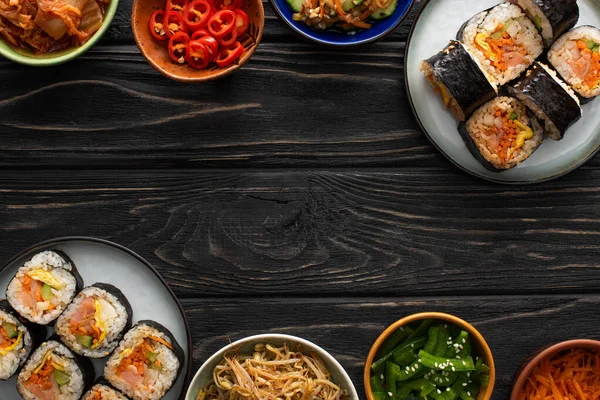 Vue de dessus des assiettes avec gimbap coréen et plats d'accompagnement savoureux sur la surface en bois — Photo de stock