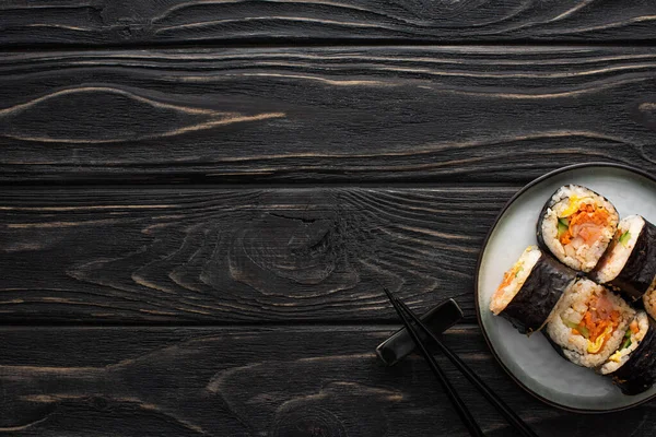 Top view of plate with korean gimbap and chopsticks on wooden surface — Stock Photo