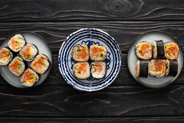 Vue de dessus des assiettes avec gimbap savoureux et coréen sur la surface en bois — Photo de stock