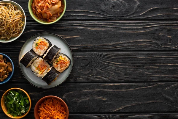 Vista superior da placa com gimbap fresco perto de pratos laterais coreanos na superfície de madeira — Fotografia de Stock