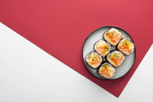 Top view of plate with gimbap on white and crimson — Stock Photo