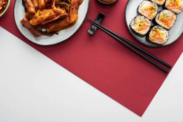 Vista superior de tteokbokki fresco e gimbap coreano em branco e carmesim — Fotografia de Stock