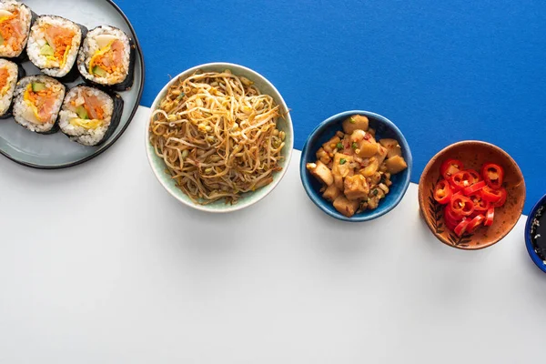 Top view of plate with gimbap near korean side dishes on white and blue — Stock Photo