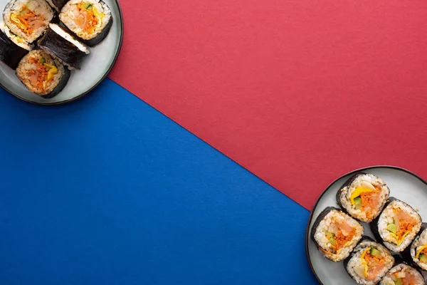 Top view of plates with gimbap on crimson and blue — Stock Photo