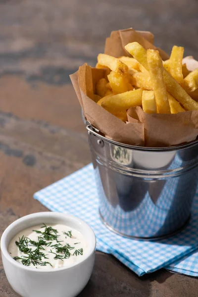 Bucket with tasty french fries and creamy garlic sauce on marble surface — Stock Photo