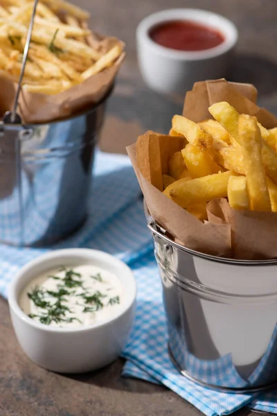 Selective focus of bucket with tasty french fries and creamy garlic sauce — Stock Photo