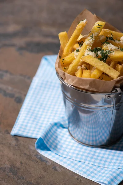 Bucket of salty french fries near cotton napkin on marble surface — Stock Photo