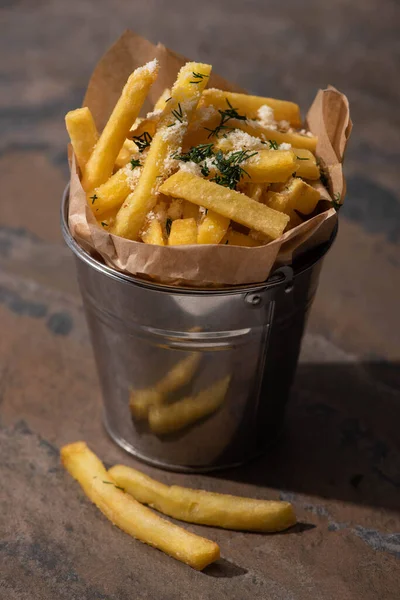 Bucket of salty french fries on marble surface — Stock Photo