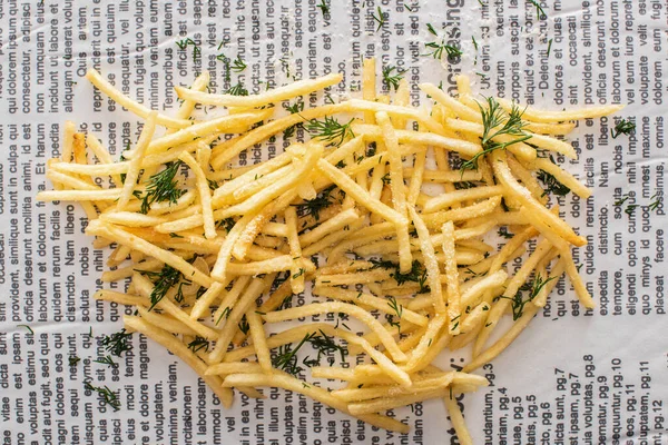 Vista dall'alto di patatine fritte croccanti con aneto sul giornale — Foto stock