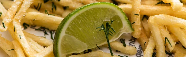 Panoramic shot of lime near crispy french fries with dill — Stock Photo