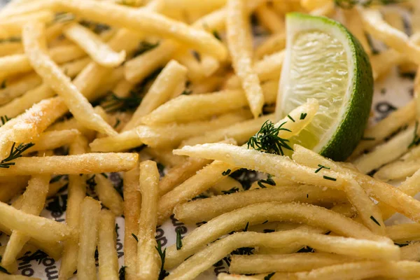 Close up of sliced lime near crispy french fries with dill — Stock Photo