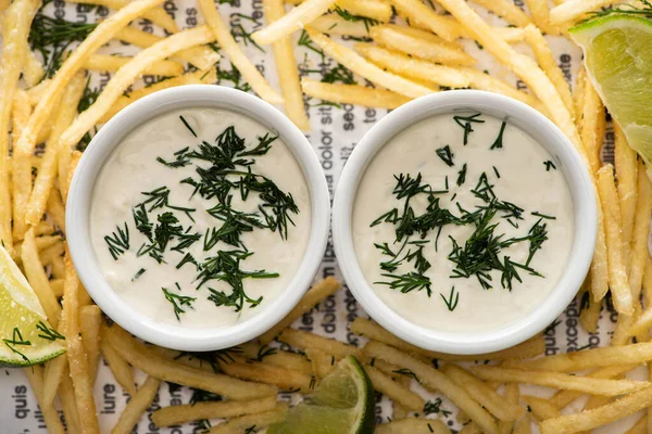 Vista superior de molho de alho cremoso com endro perto de batatas fritas crocantes — Fotografia de Stock
