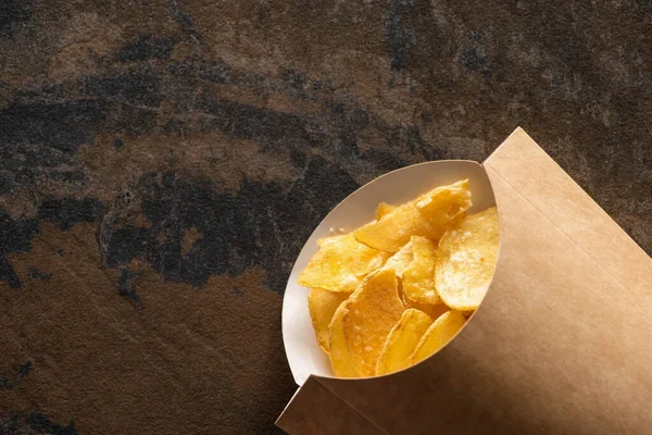 Top view of crunchy potato chips with salt on marble surface — Stock Photo