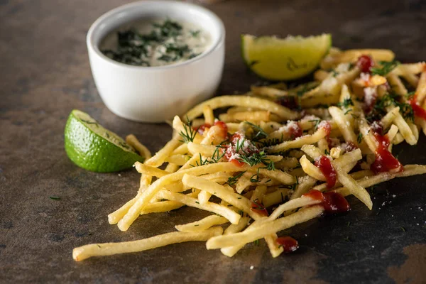 Selective focus of french fries with ketchup, salt and dill near lime and garlic sauce on marble surface — Stock Photo