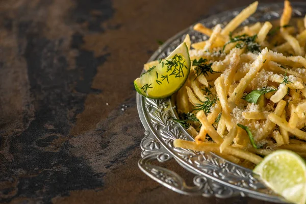 Foco seletivo de batatas fritas salgadas e limão fatiado na superfície de mármore — Fotografia de Stock