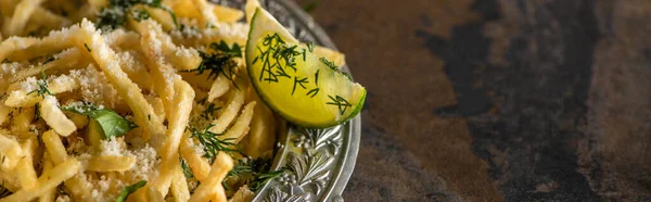 Panoramic shot of salted french fries and sliced lime on marble surface — Stock Photo