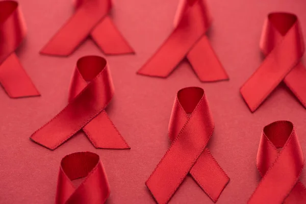 Selective focus of red awareness aids ribbons on red background — Stock Photo