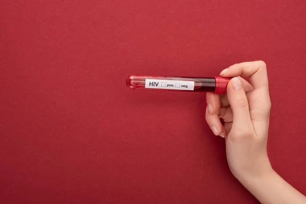 Cropped view woman holding blood sample in test tube with hiv lettering on red background — Stock Photo