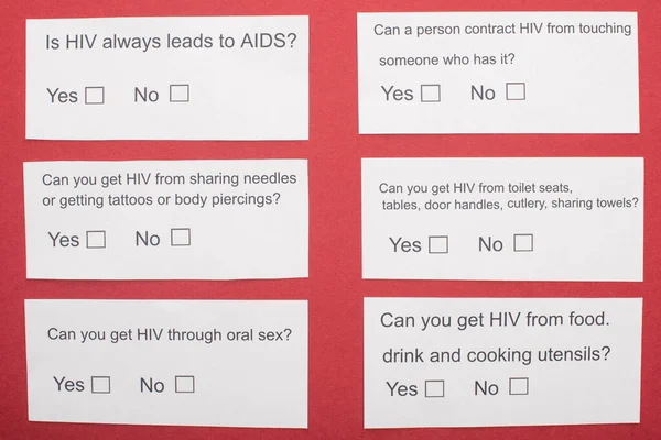 Top view of paper cards with HIV questionnaire on red background — Stock Photo